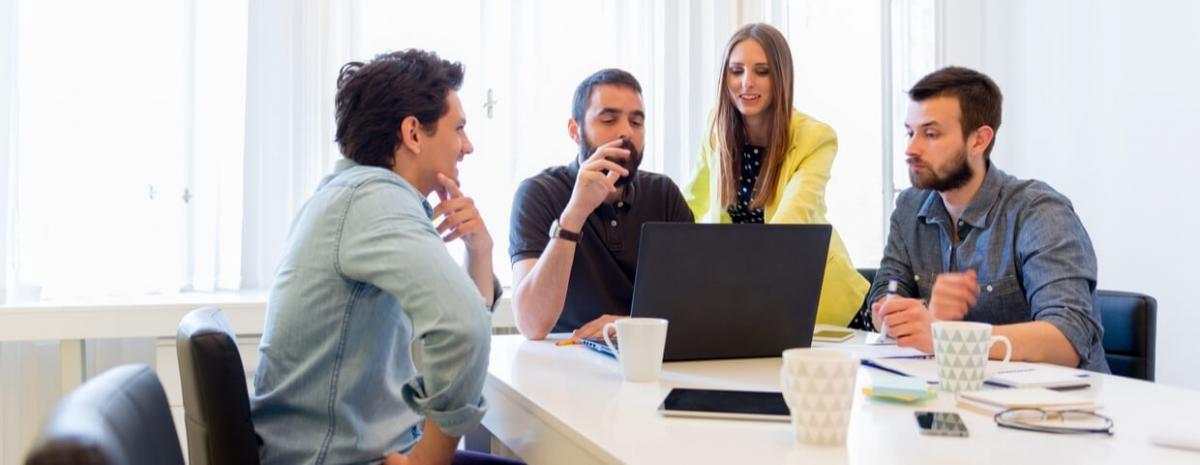 Four people talking around table in room.