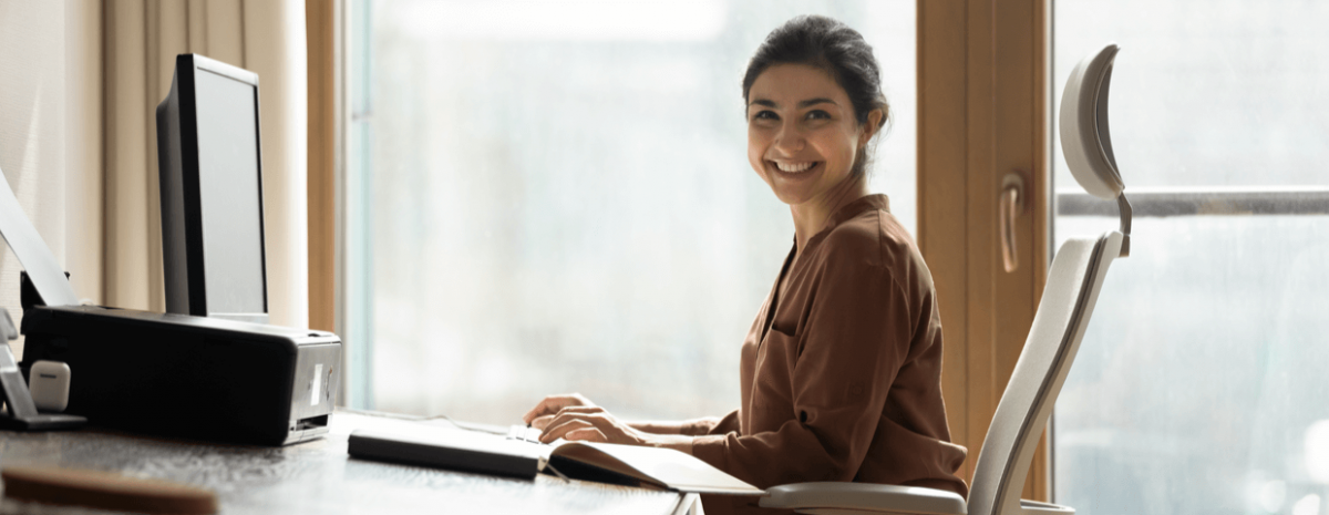 Young woman smiling, sitting on chair at office desk.