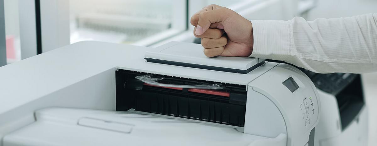 Man placing his fist on top of printer.